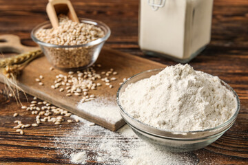 Bowl with wheat flour on wooden background