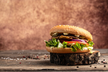 Homemade burger with grilled meat, vegetables, sauce on rustic wooden background. fast food and junk food concept