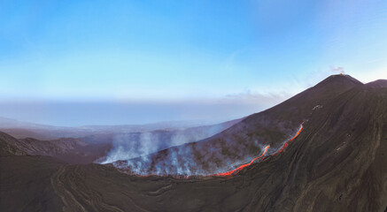 Etna top view  with lava flow and smoke with blue sky during blue hour- Aerial panorama at sunset