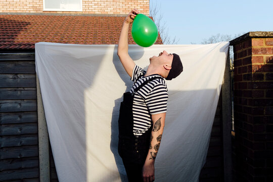 Man with mouth open holding green balloon at back yard