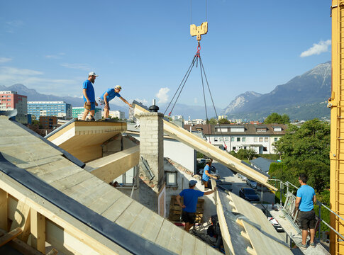 Blue-collar workers at construction site standing on rooftop