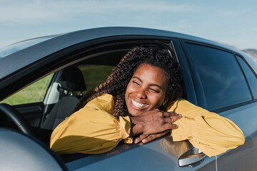 Happy woman leaning out of car's window on sunny day