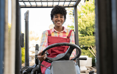 Happy gardener driving forklift at nursery