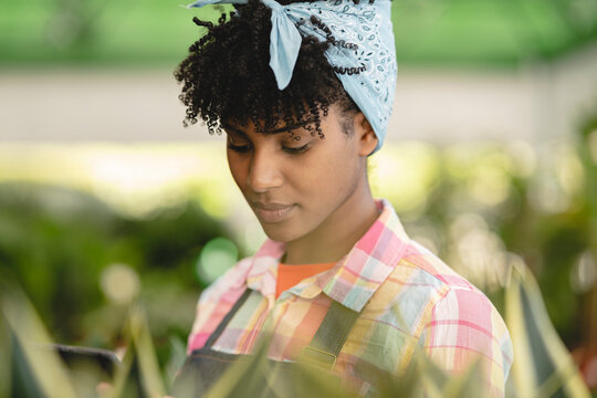 Gardener with curly hair working on tablet PC at plant nursery