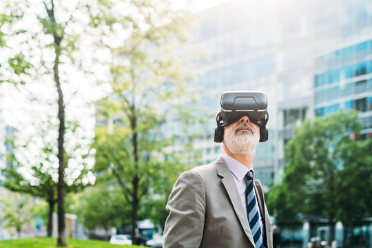 Mature businessman wearing virtual reality simulator on sunny day