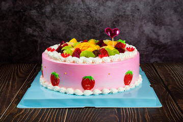 pink fruit cake with strawberry,mango,kiwi fruit on wooden table