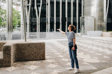 Woman checking for rain standing outside office building
