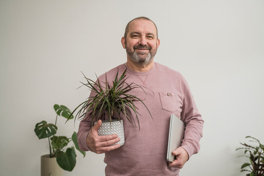 Smiling businessman with dragon tree and laptop at office