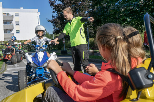 Young instructor assisting boy driving quadbike at traffic education training