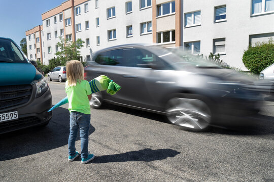 Boy holding school cone on road stopping for speeding car