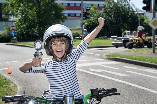 Happy boy holding trophy sitting on quadbike