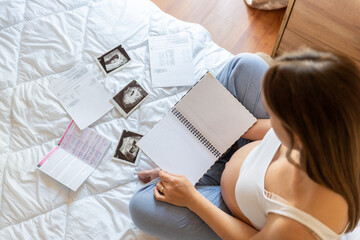 Fototapeta na wymiar Pregnancy list woman writing. Beautiful pregnant woman writing check list. Happy pregnancy lady holding notepad. Concept maternity, childbirth.