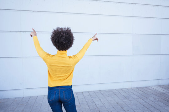 Young Woman Pointing Facing Towards Wall