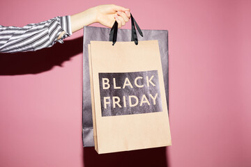 Close-up of unrecognizable woman buying clothes at Black Friday sale, she holding paper bags...