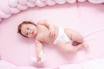 young mom wiping the baby skin body and face with wet wipes carefully on pink background. concept...