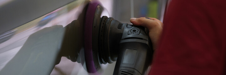 A man polishes the body of a car, hands close-up