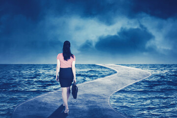 Businesswoman walking on the road above the sea