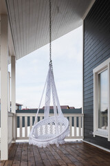 Trendy hanging chair on the veranda of a country house.