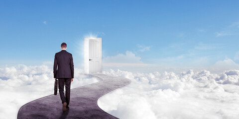 Male manager walking toward a bright door in sky