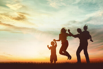 Silhouette of happy family jumping together at park