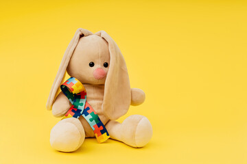 Plush bunny with puzzle pattern ribbon. World autism awareness and pride day