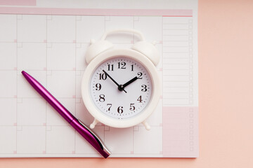 Fototapeta na wymiar Planner, pencil and alarm clock on the pink background, planning for business meeting or travel planning concept