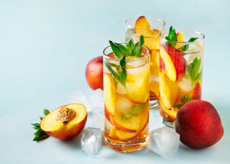 Peach drink, beverage with mint leaf, ice and fruit on blue background