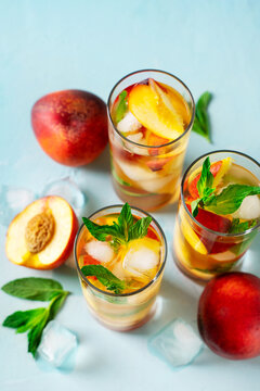 Peach drink, beverage with mint leaf, ice and fruit on blue background