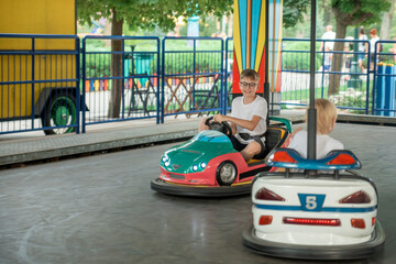 Boys driving cars in an amusement park. Have fun weekend at the theme park. Children competing on...