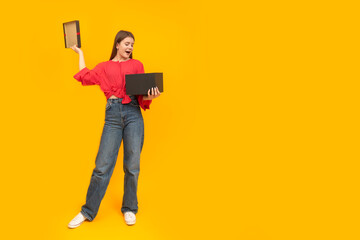Enthusiastic young girl holds an open gift. Woman with large black box on bright yellow background. Copy space