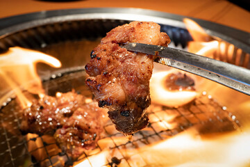 トングで持ち上げる中落ちカルビ  焼肉　アップ