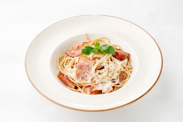 Pasta with parmesan bacon and white sauce on a white background