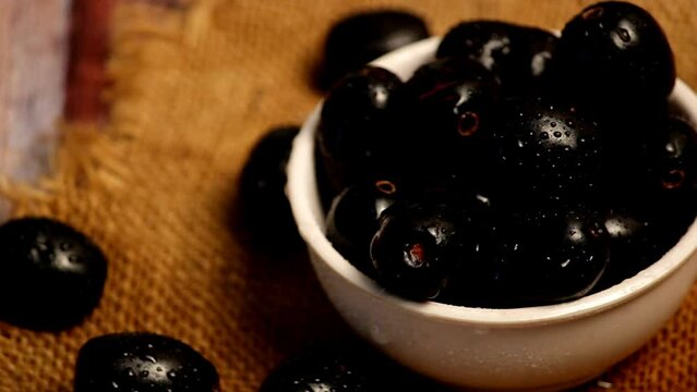Bilberry with water drops, black jamun fruit on wooden background,fresh Ripe Sweet Blueberries Covered with Water Drops