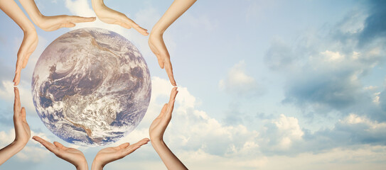 Earth globe in human hands against sky background