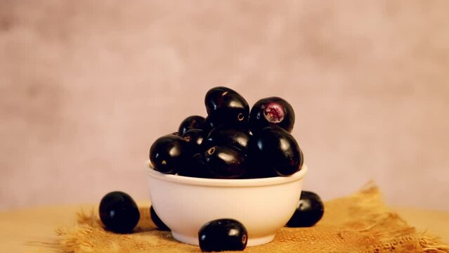 Rotating fresh jamun fruit on the dark background,turning indian blueberries on table,selective focus