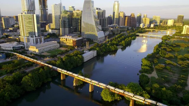 Aerial view of a long train arriving in Austin Texas, sunny summer evening in USA - tilt, drone shot