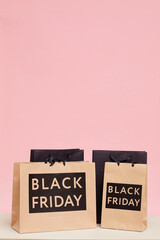 Background image of shopping paper bags with Black Friday lettering against pink wall in womens store