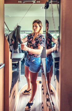 Young Woman Hanging Clothes On A Clothesline Inside Her Camper Van During A Trip