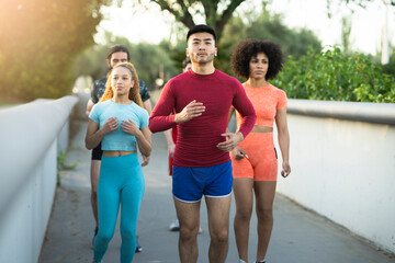 Group of young multiracial sportsmen running outdoors. Street sport - focus on asian man -