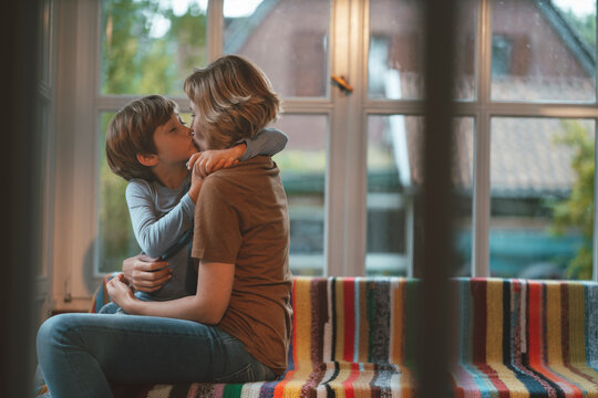 Affectionate mother and son kissing sitting on sofa at home