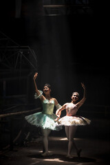 Fototapeta na wymiar Two young Asian Ballet dancers perform in dark room