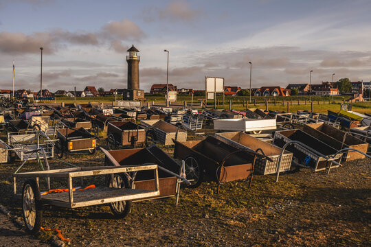 Germany, Lower Saxony, Juist, Collection of empty push carts standing in front of Memmertfeuer lighthouse at dusk