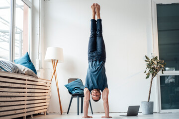 Man practicing handstand in front of wall at home