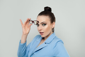 Surprised young woman in glasses over gray background