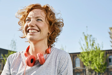 Portrait of happy young woman with headphones in urban surrounding