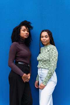 Female friends standing in front of blue wall