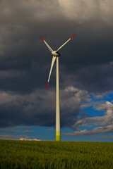 Fototapeta premium Windräder in der Landwirtschaft im Sommerwind dunkeler Himmel Wolken Energie von morgen im Getreidefeld Sturm am Windrad 