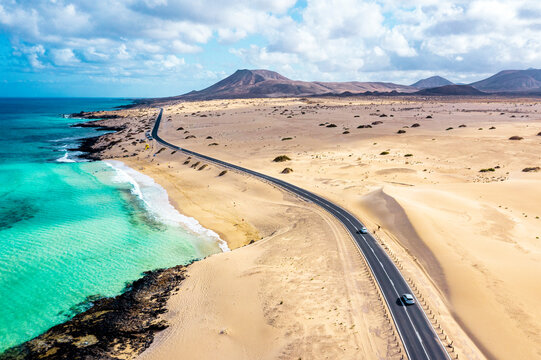Aerial view of road crossing the desert overlooking the crystal sea, Corralejo Natural Park, Fuerteventura, Canary Islands, Atlantic