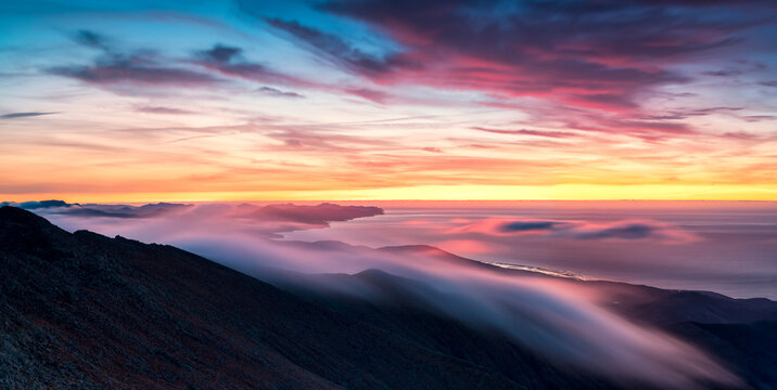 Long exposure of clouds and mist in the multicolored sky at dawn over Pico de la Zarza, Fuerteventura, Canary Islands, Atlantic