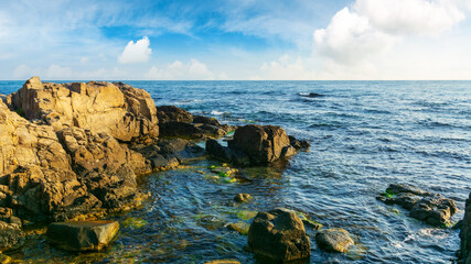 rocky sea coast in morning light. summer vacation concept. beautiful nature scenery with clouds on the blue sky above horizon
